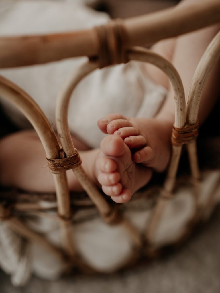 Geborgenheit von Anfang an Kleine Babyfüße ragen aus einem geflochtenen Babykorb