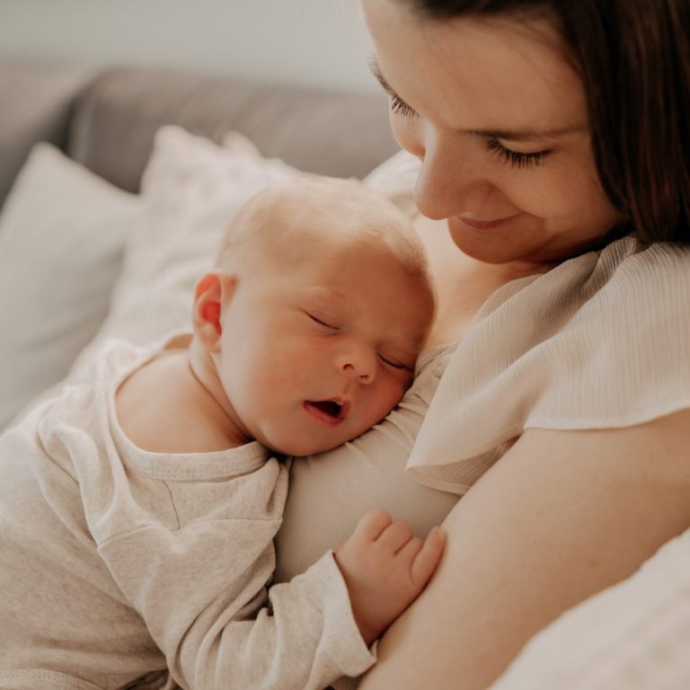Geborgenheit und Nähe in der Babyzeit Bindungsorientierte Mutter hält ihr schlafendes Baby liebevoll im Arm