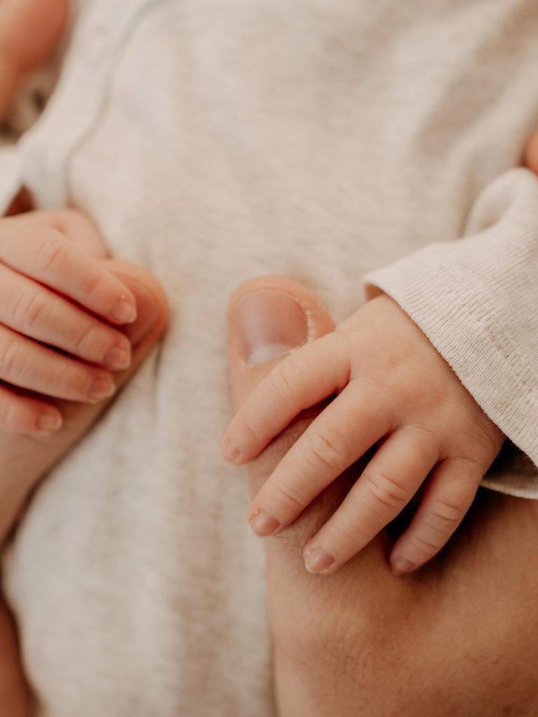Bindung beginnt mit Berührung Babyhand greift schützend nach dem Finger eines Erwachsenen